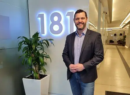 Smiling businessman in a corridor standing next to an illuminated 181 sign