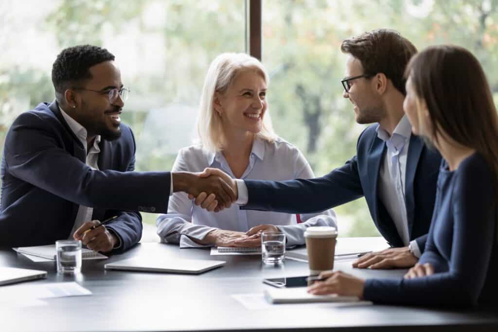 Smiling diverse businesspeople shake hands get acquainted greeting at a commercial advisory meeting.